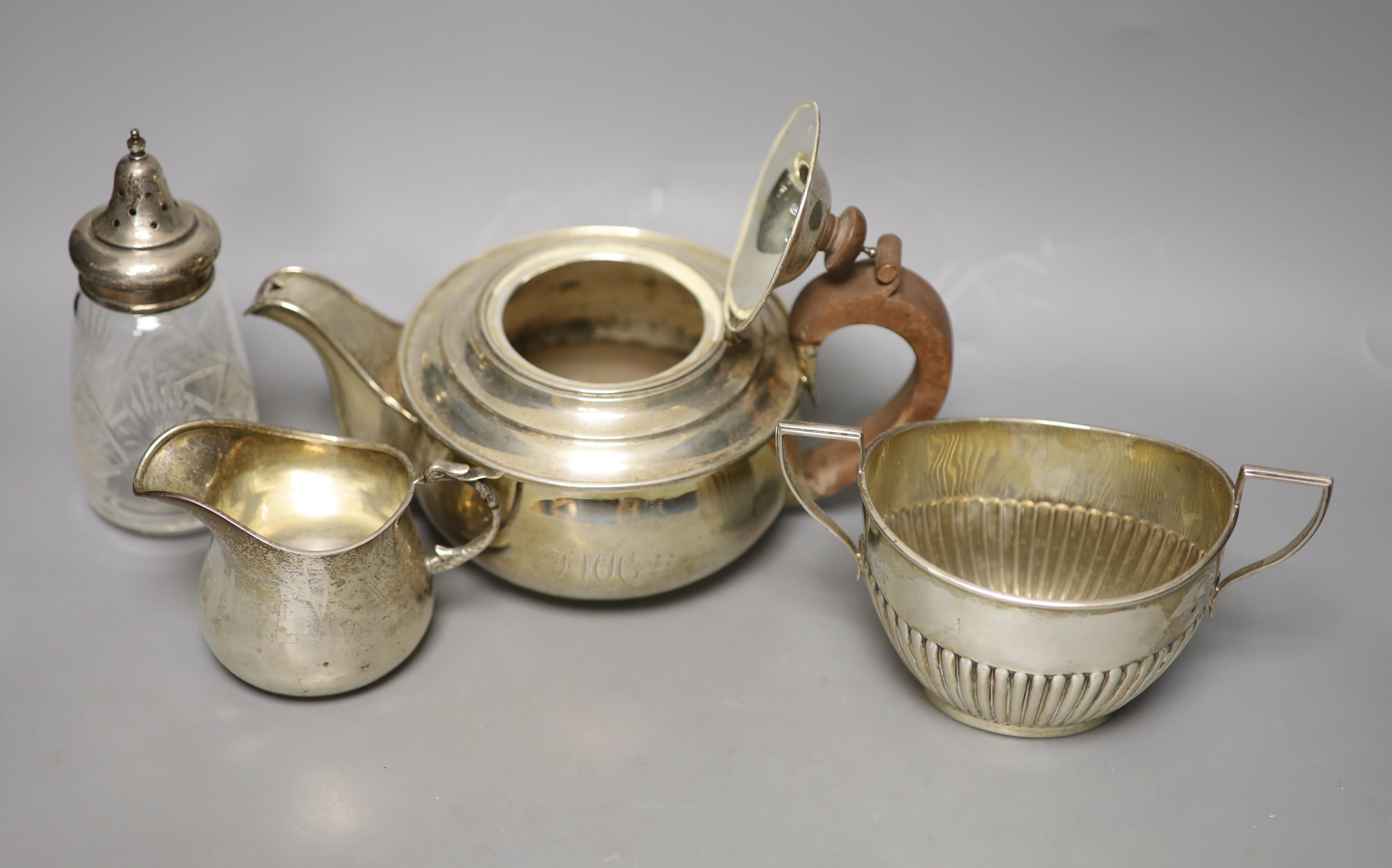 A George V silver teapot, Birmingham, 1913, a similar cream jug and sugar bowl and a silver mounted glass sugar sifter